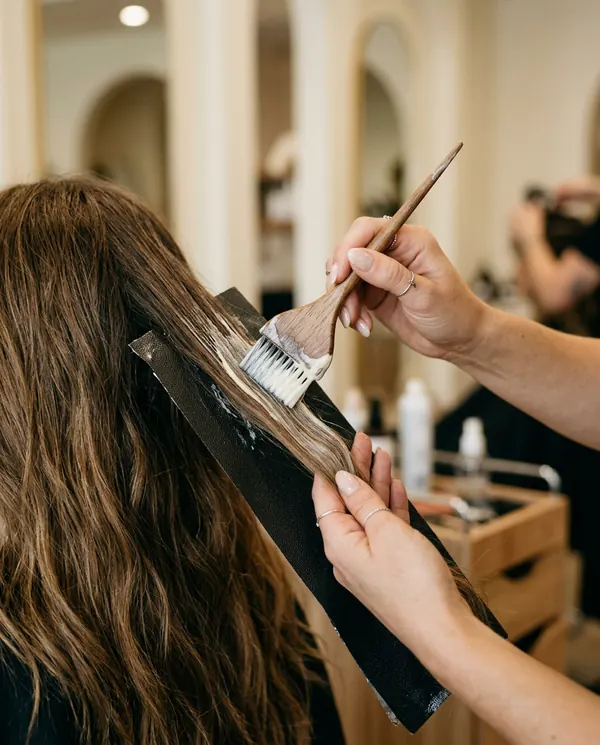 Stylist hand-painting balayage color onto long hair